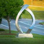 Dancing Triangles, a stainless steel piece by Kevin Robb, entry to Fox Lake Plaza, median on 2nd near I-35